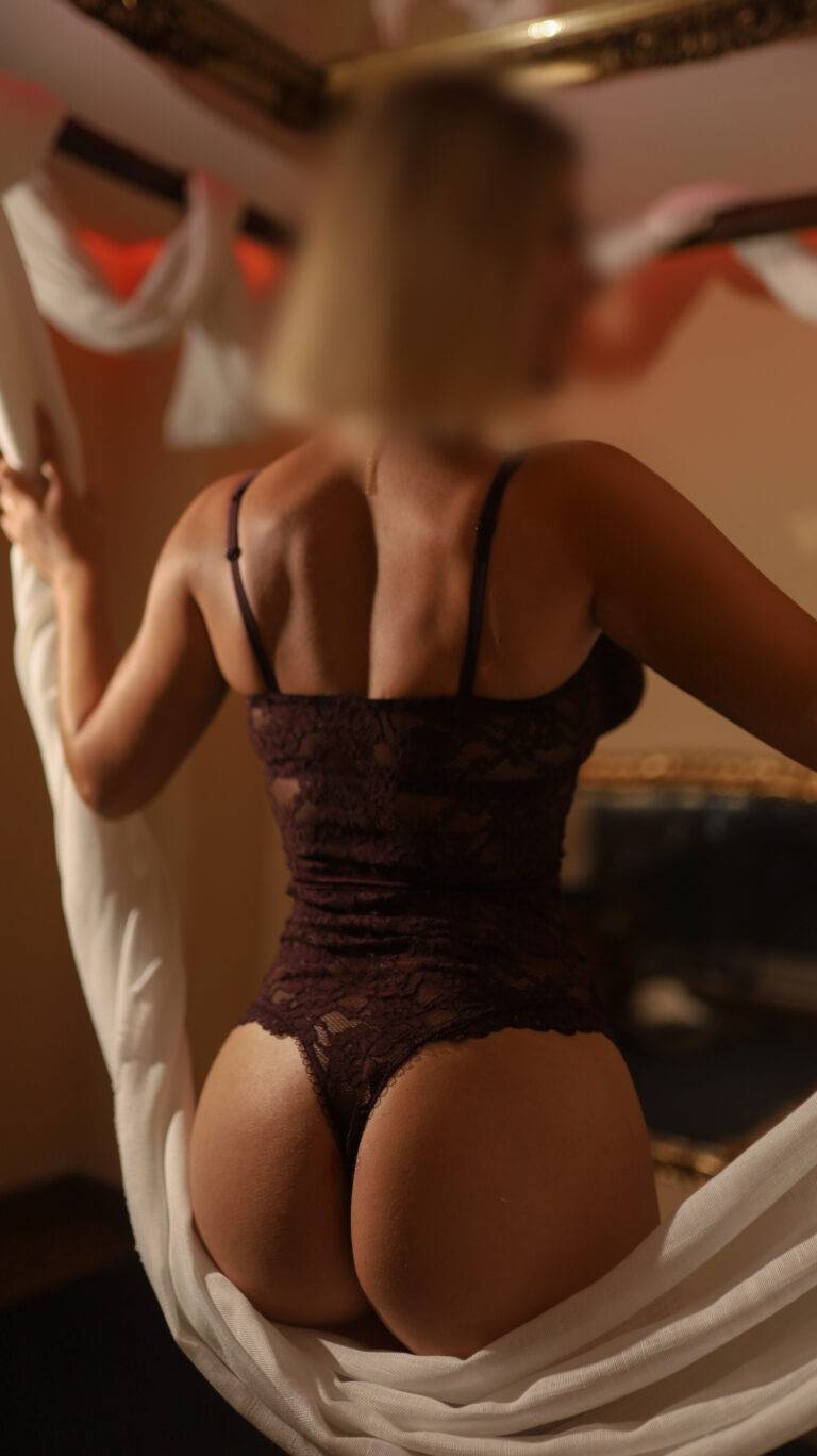 Laura, tantric masseuse in Marbella, posing with a white drape in a warm treatment room