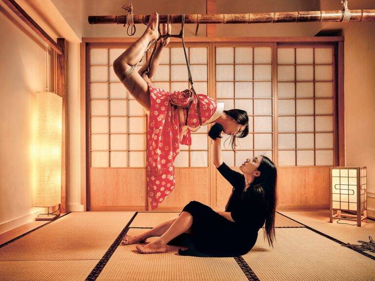 Shibari suspension in a Japanese tatami room, rope artist guiding a model in a red kimono at Tantra Marbella
